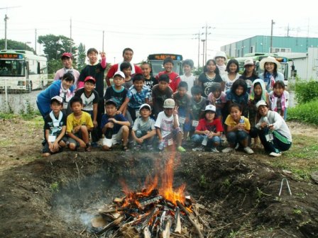 縄文土器を焼いている周りに集まる子どもたちの集合写真