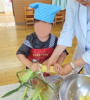 トウモロコシの皮をむく園児の写真その1