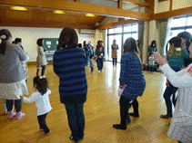 室内で踊っている人々とこどもの姿が見える風景。