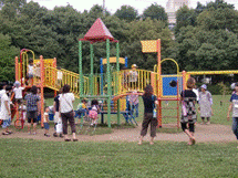 公園の遊具で遊ぶこどもたちと大人たちの様子が写っている画像。