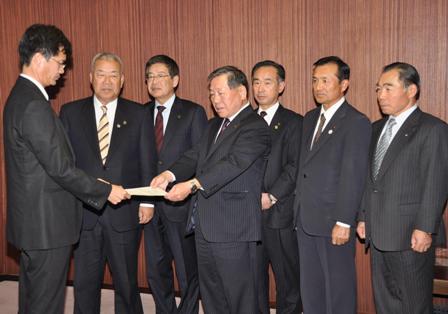 複数のビジネスマンが書類を手渡ししている場面の画像。