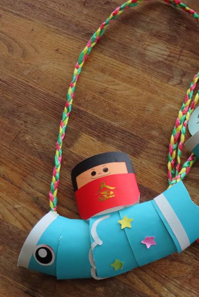 青い魚の形をしたおもちゃの中に小さな人形が座っている画像。