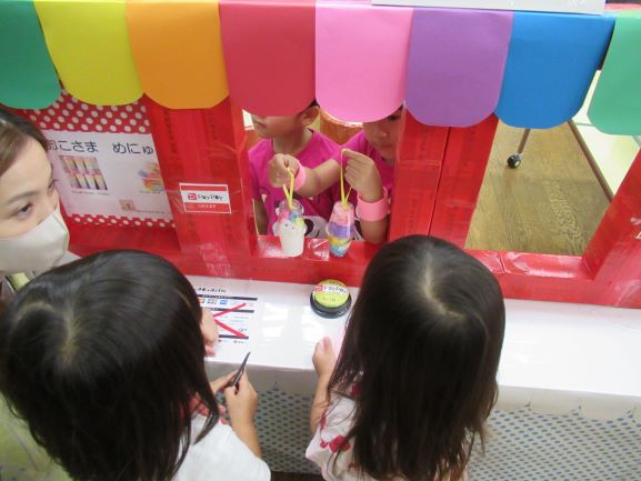 こどもたちがカラフルな屋台で遊んでいる様子が映っている画像です