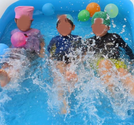 水の中で遊んでいる3人のこどもたちが写っている画像
