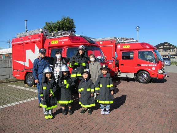 赤い消防車の前に立つ大人とこどもたちのグループの写真