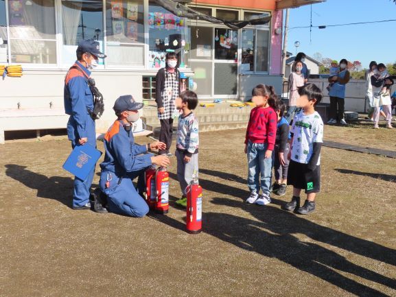 消防士がこどもたちに消火器の使い方を教えている場面。