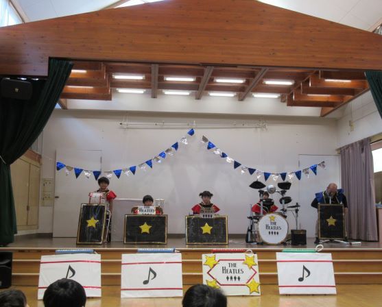 こどもたちがステージで楽器を演奏している様子が描かれている画像