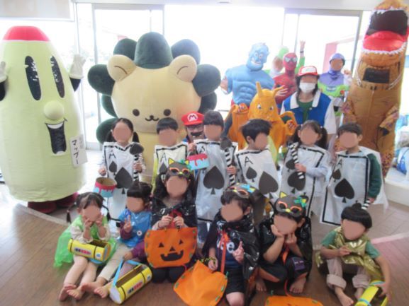 こどもたちがコスチュームを着てキャラクターたちと一緒にポーズをとっている様子の写真。