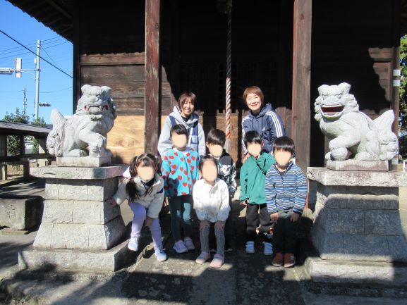こどもたちが狛犬の前でポーズをとっている写真。