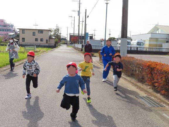 こどもたちが赤い帽子をかぶって道路を走っている様子。