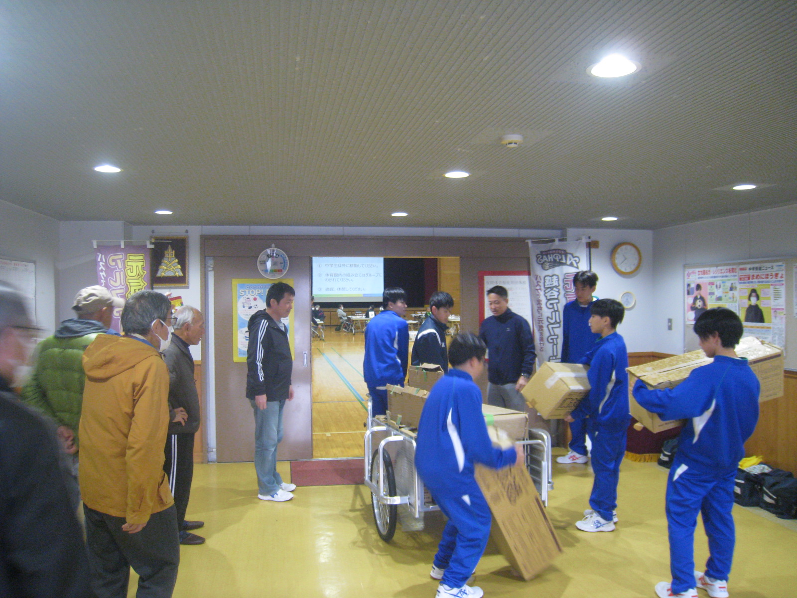 こどもたちが作業を手伝っている室内の様子で、数人が物を運んでいる。