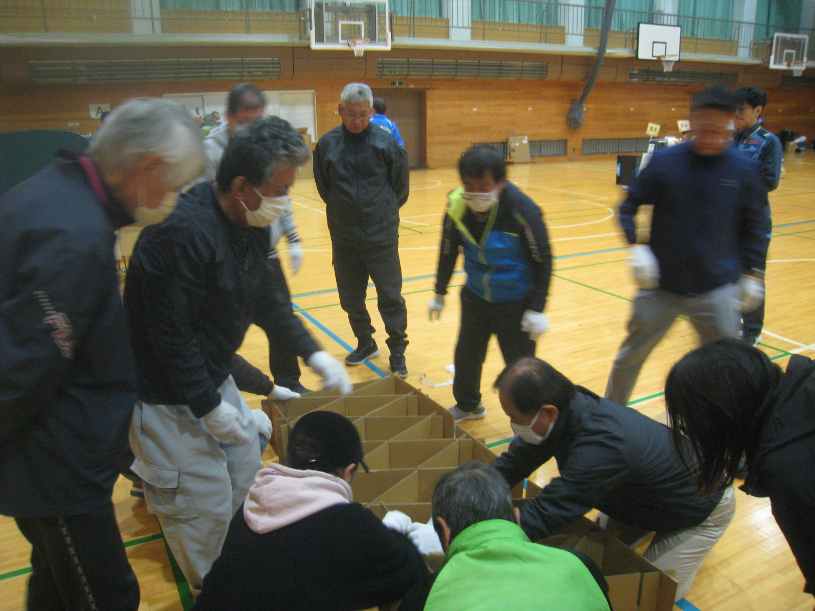 体育館で数人が協力して作業をしている様子。