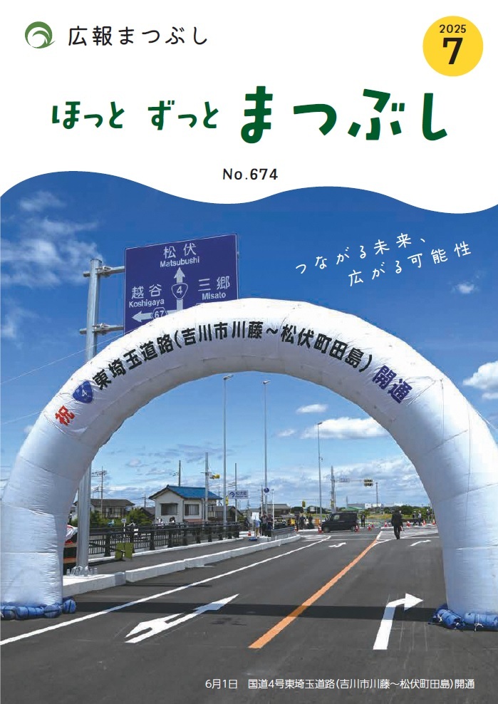 道路の上に大きな白いアーチが設置され開通式のような雰囲気の街並みと青空の写真