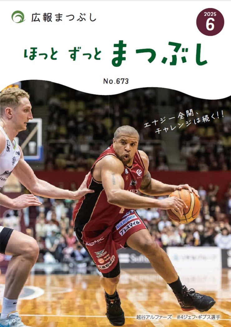 屋内のバスケットコートで栗色のユニフォームを着た選手がボールを持ってドリブルするところを白いユニフォームの相手選手が守り観客が背景にいる